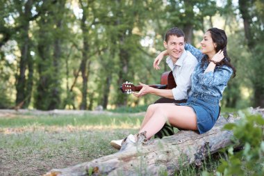 bir günlük ormanın içinde oturan ve iskambil gitar, yaz doğa, romantik duygular genç çift