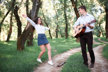ormanda yürüyüş ve iskambil gitar, yaz doğa, parlak güneş ışığı genç çift, gölgeler ve yeşil yaprakları, romantik duygular