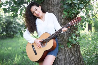 ormanda yürüyüş ve iskambil gitar, yaz doğa, parlak güneş ışığı, gölgeler ve yeşil yaprakları, romantik duygular genç kadın