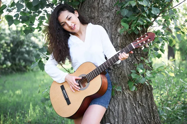 ormanda yürüyüş ve iskambil gitar, yaz doğa, parlak güneş ışığı, gölgeler ve yeşil yaprakları, romantik duygular genç kadın