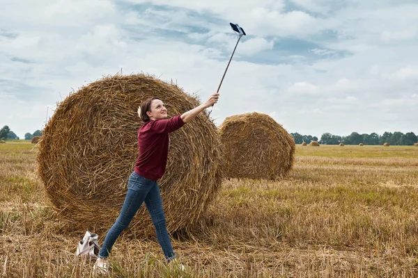 若い女の子 干し草の背景にスマート フォン上の Selfie — ストック写真