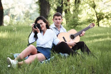 ormanda yürüyüş ve fotoğrafta eski fotoğraf makinesi, yaz doğa, parlak güneş ışığı, gitar, çalmak genç çift gölgeler ve yeşil yaprakları, romantik duygular