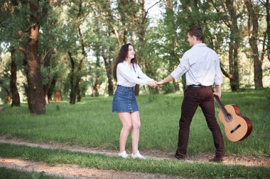 ormanda yürüyüş ve iskambil gitar, yaz doğa, parlak güneş ışığı genç çift, gölgeler ve yeşil yaprakları, romantik duygular