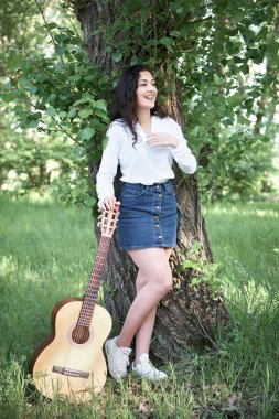 ormanda yürüyüş ve iskambil gitar, yaz doğa, parlak güneş ışığı, gölgeler ve yeşil yaprakları, romantik duygular genç kadın