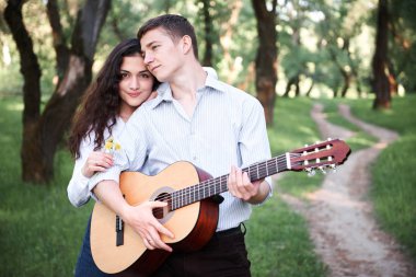 ormanda yürüyüş ve iskambil gitar, yaz doğa, parlak güneş ışığı genç çift, gölgeler ve yeşil yaprakları, romantik duygular