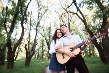 ormanda yürüyüş ve iskambil gitar, yaz doğa, parlak güneş ışığı genç çift, gölgeler ve yeşil yaprakları, romantik duygular