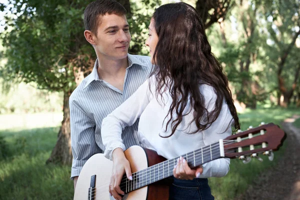 Genç çift, ormanda yürüyüş gitar çalmak ve dans, yaz doğa, parlak güneş ışığı, gölgeler ve yeşil yaprakları, romantik duygular