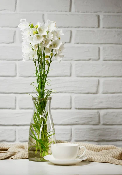 beyaz çiçek ve Kupası olduğunu örgü yün, tuğla duvar arka plan ile masada