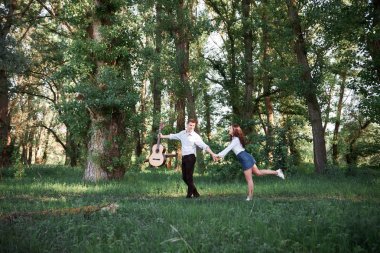 ormanda yürüyüş ve iskambil gitar, yaz doğa, parlak güneş ışığı genç çift, gölgeler ve yeşil yaprakları, romantik duygular