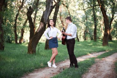 ormanda yürüyüş ve iskambil gitar, yaz doğa, parlak güneş ışığı genç çift, gölgeler ve yeşil yaprakları, romantik duygular