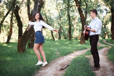 ormanda yürüyüş ve iskambil gitar, yaz doğa, parlak güneş ışığı genç çift, gölgeler ve yeşil yaprakları, romantik duygular
