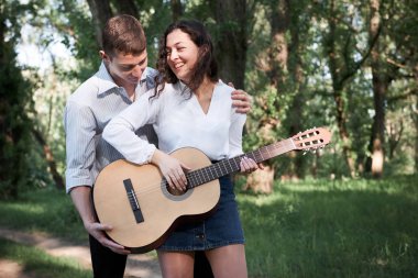 Genç çift, ormanda yürüyüş gitar çalmak ve dans, yaz doğa, parlak güneş ışığı, gölgeler ve yeşil yaprakları, romantik duygular