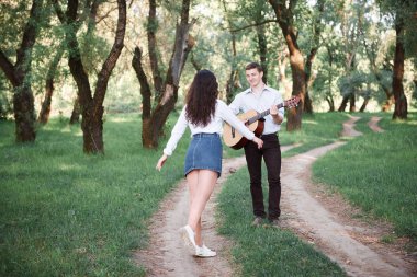 ormanda yürüyüş ve iskambil gitar, yaz doğa, parlak güneş ışığı genç çift, gölgeler ve yeşil yaprakları, romantik duygular