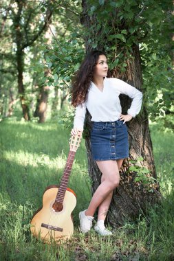 ormanda yürüyüş ve iskambil gitar, yaz doğa, parlak güneş ışığı, gölgeler ve yeşil yaprakları, romantik duygular genç kadın