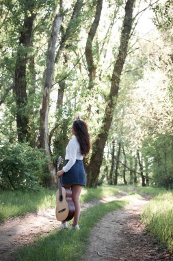 ormanda yürüyüş ve iskambil gitar, yaz doğa, parlak güneş ışığı, gölgeler ve yeşil yaprakları, romantik duygular genç kadın