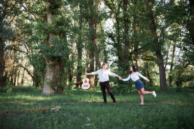 ormanda yürüyüş ve iskambil gitar, yaz doğa, parlak güneş ışığı genç çift, gölgeler ve yeşil yaprakları, romantik duygular