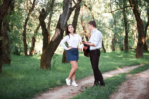 年轻夫妇漫步在森林里玩吉他 夏日的自然 灿烂的阳光 阴影和绿叶 浪漫的感觉 — 图库照片