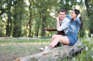 bir günlük ormanın içinde oturan ve iskambil gitar, yaz doğa, romantik duygular genç çift