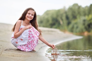 nehirde gemi yelken bir oyuncakla oynayan kız