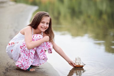 nehirde gemi yelken bir oyuncakla oynayan kız