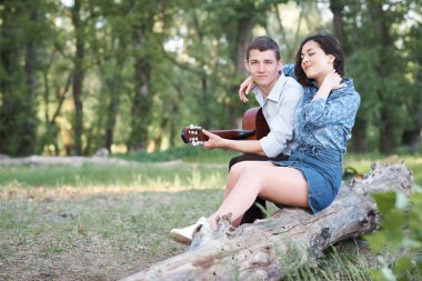 bir günlük ormanın içinde oturan ve iskambil gitar, yaz doğa, romantik duygular genç çift