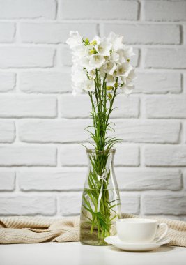 beyaz çiçek ve Kupası olduğunu örgü yün, tuğla duvar arka plan ile masada