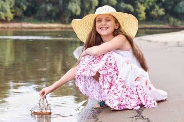 nehirde gemi yelken bir oyuncakla oynayan kız