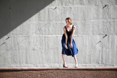 Genç kız bir beton duvara poz giyinmiş siyah, sert ışık ve gölge