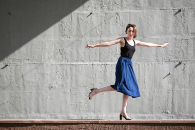 Genç kız bir beton duvara poz giyinmiş siyah, sert ışık ve gölge