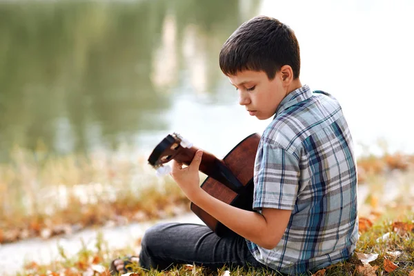 Jongen Een Akoestische Gitaar Speelt Zit Aan Oever Van Rivier — Stockfoto