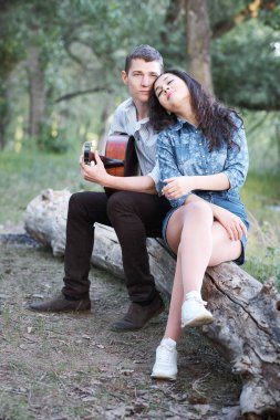 bir günlük ormanın içinde oturan ve iskambil gitar, yaz doğa, romantik duygular genç çift