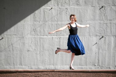 Genç kız bir beton duvara poz giyinmiş siyah, sert ışık ve gölge