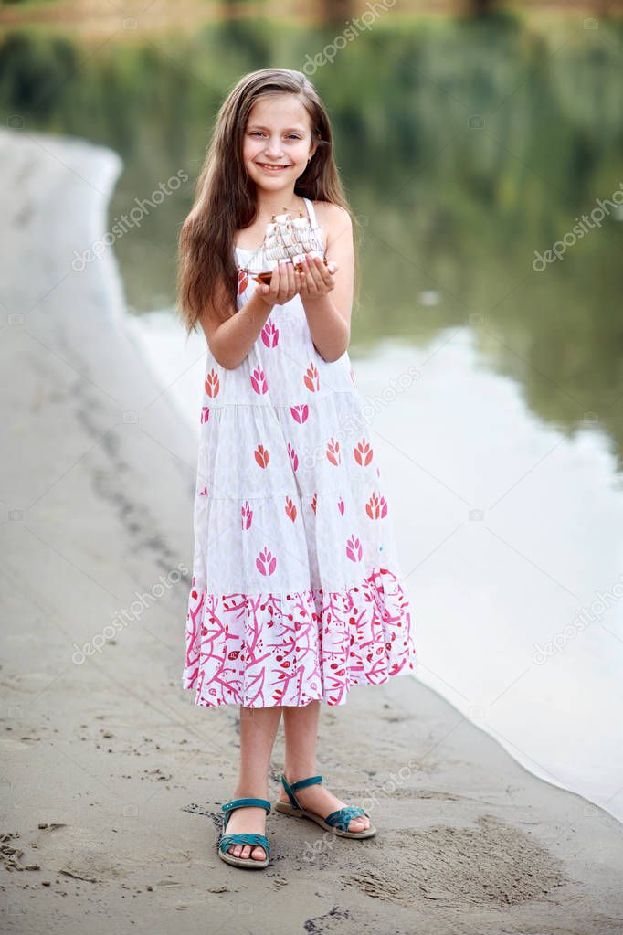 girl playing with a toy sailing ship by the river