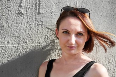 Genç kız bir beton duvara poz giyinmiş siyah, sert ışık ve gölge