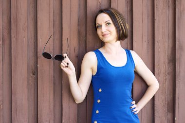 Genç kız kırmızı kahverengi ahşap arka plan üzerinde mavi uzun elbise poz