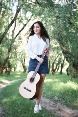 ormanda yürüyüş ve iskambil gitar, yaz doğa, parlak güneş ışığı, gölgeler ve yeşil yaprakları, romantik duygular genç kadın