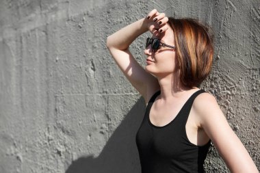 Genç kız bir beton duvara poz giyinmiş siyah, sert ışık ve gölge