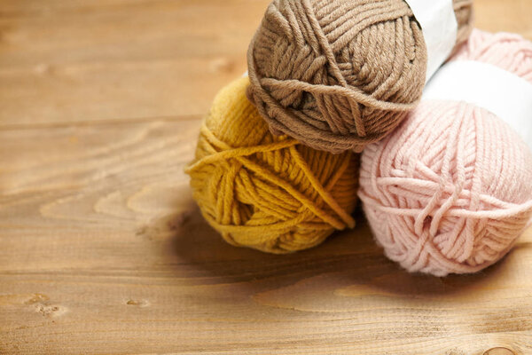 colorful wool threads for knitting on wooden background