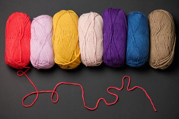 balls of woolen thread for knitting on black background