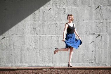 Genç kız bir beton duvara poz giyinmiş siyah, sert ışık ve gölge