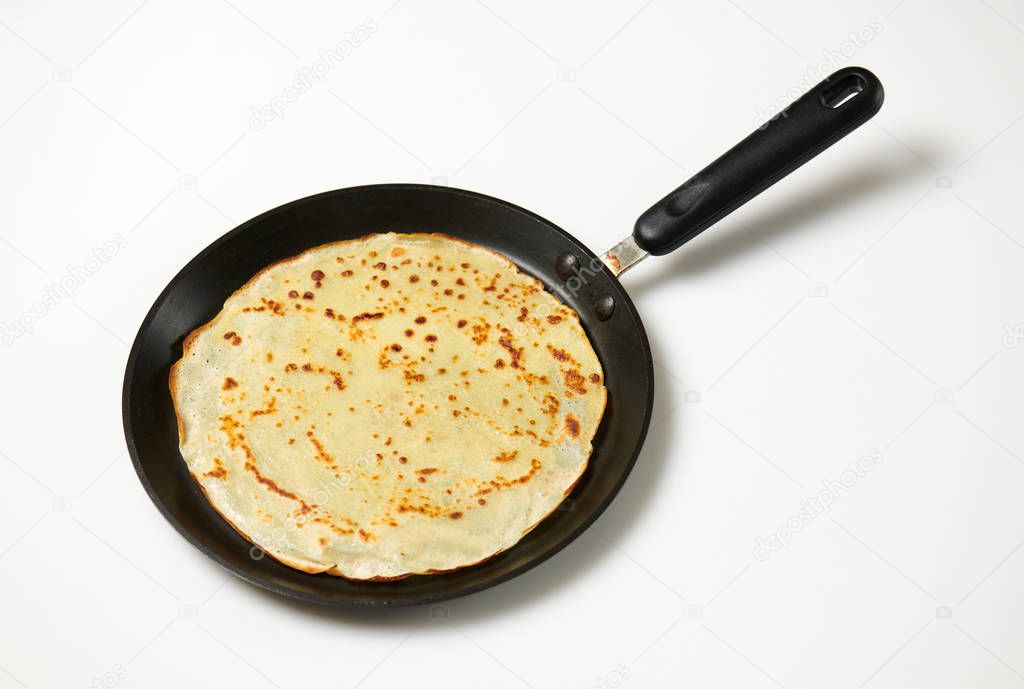 Crepe closeup, thin pancake on a frying pan, white background