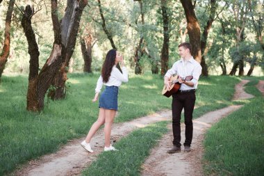 ormanda yürüyüş ve iskambil gitar, yaz doğa, parlak güneş ışığı genç çift, gölgeler ve yeşil yaprakları, romantik duygular