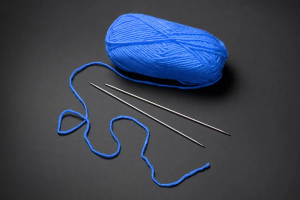 blue ball of woolen thread for knitting on black background