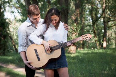 Genç çift, ormanda yürüyüş gitar çalmak ve dans, yaz doğa, parlak güneş ışığı, gölgeler ve yeşil yaprakları, romantik duygular