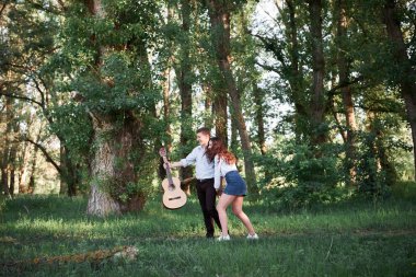 ormanda yürüyüş ve iskambil gitar, yaz doğa, parlak güneş ışığı genç çift, gölgeler ve yeşil yaprakları, romantik duygular
