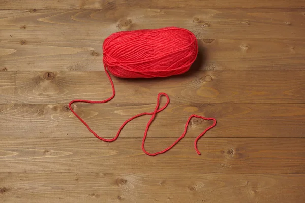 red ball of woolen thread for knitting on wooden background