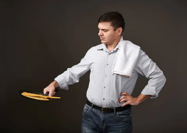 man posing with a pancake in a pan, white shirt and pants, gray background