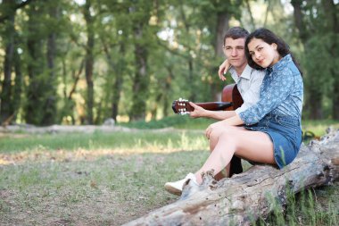 bir günlük ormanın içinde oturan ve iskambil gitar, yaz doğa, romantik duygular genç çift