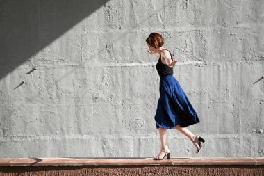 Genç kız bir beton duvara poz giyinmiş siyah, sert ışık ve gölge