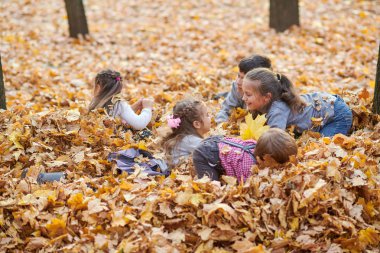 Çocuk yalan ve sonbahar Şehir Parkı içinde düşen yapraklar üzerinde oyun.